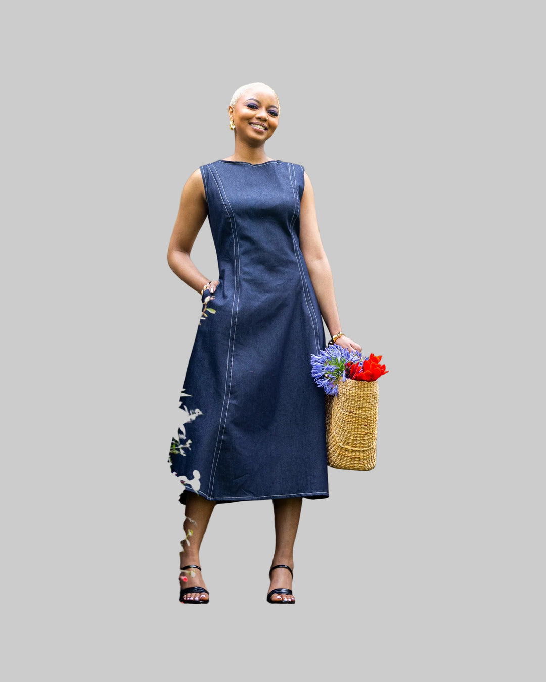 Woman in a blue dress standing on garden steps holding flowers and a basket.