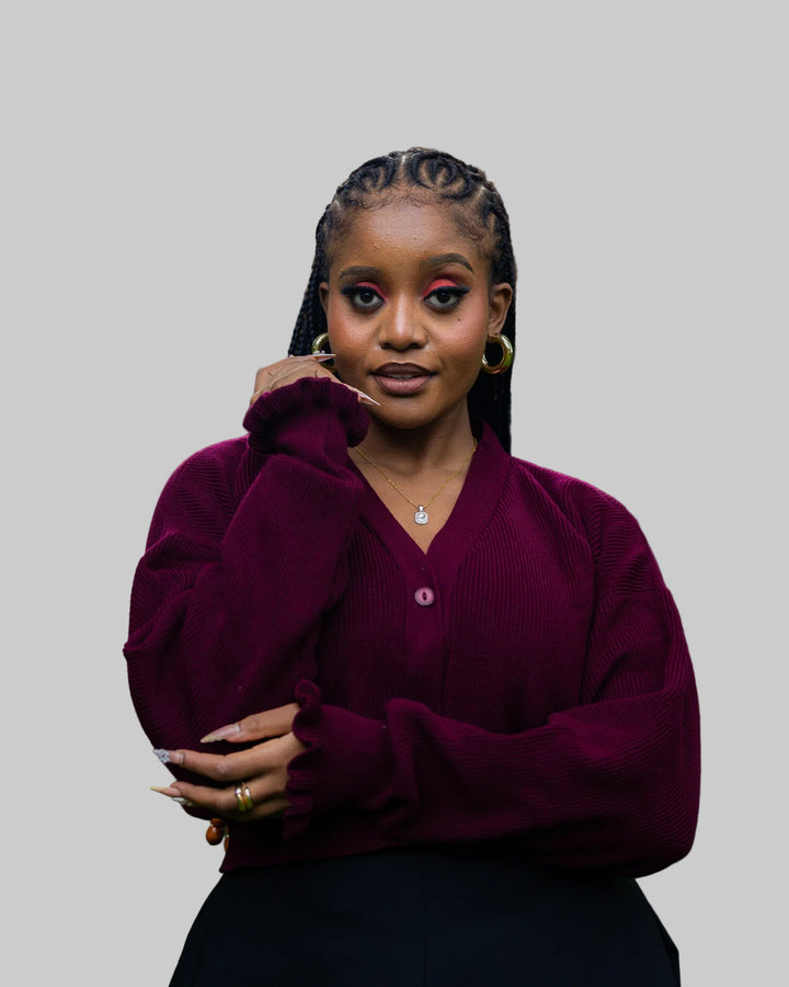 Woman wearing a burgundy sweater with a blurred outdoor background