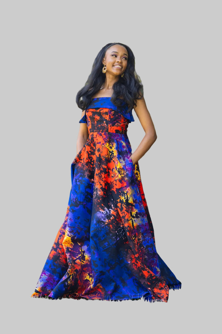 Woman in a colorful dress standing outdoors with greenery in the background